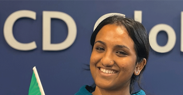 A smiling Global Guide stands in front of the UCD Global logo.